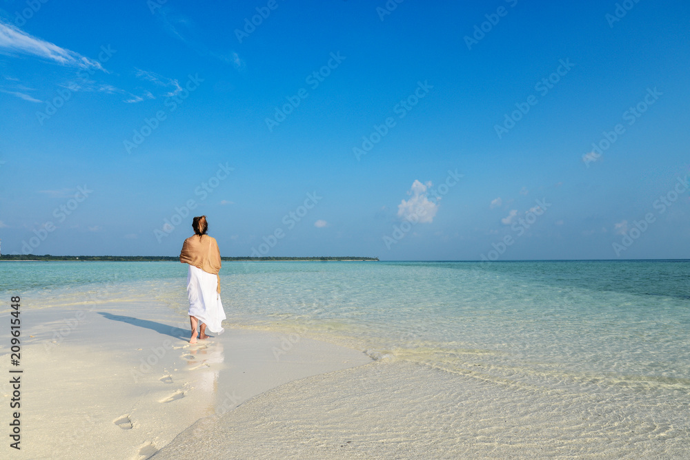 Girl in white dress walking on a sandbank Girl in white dress walking on a sandbank