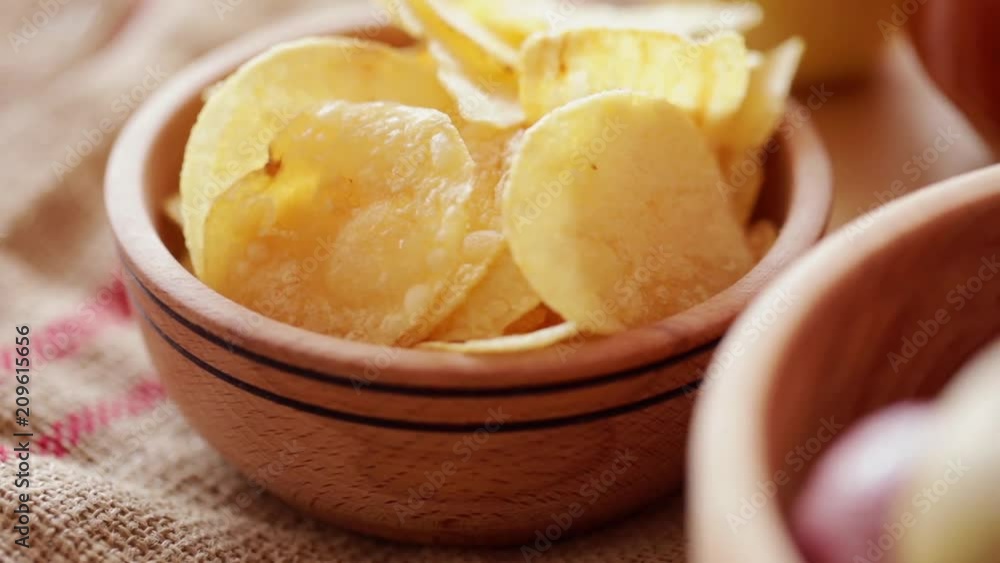 Potato chips in wooden bowl at rotating stand. Steadicam Close-up, no people. Potato chips in wooden bowl at rotating stand. Steadicam Close-up, no people.