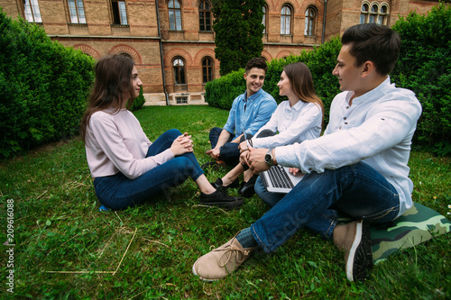 Group of young smile students sitting on the grass at talking at campus
