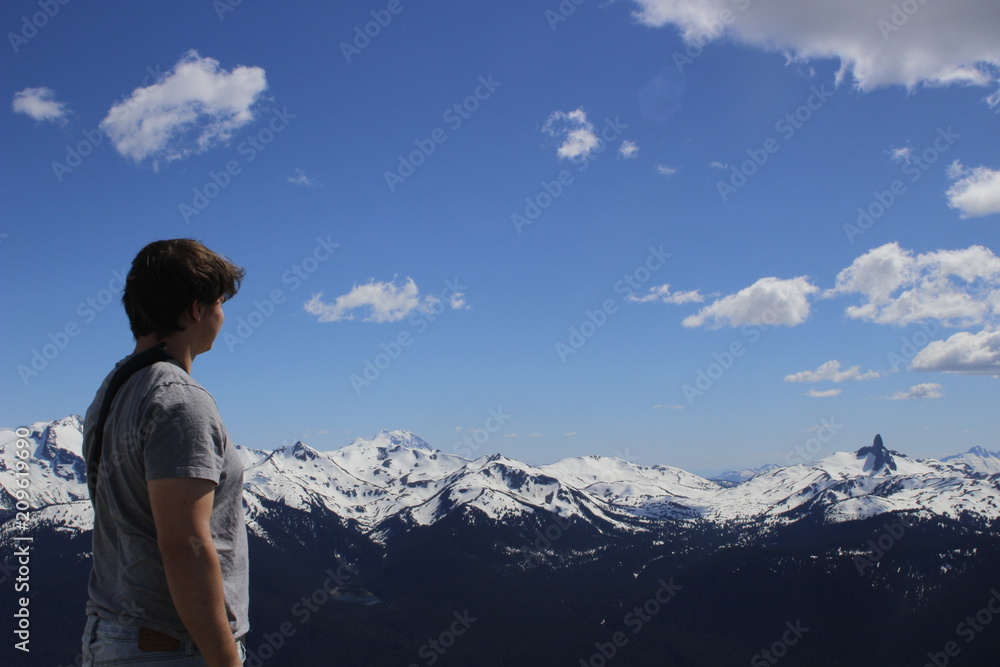 male tourist overlooks mountains at whistler in british columbia, aged 20-25