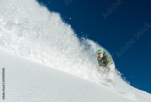 man snowboarder is going very fast freeride in stream of snow avalanche