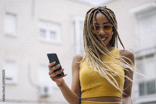 Afro-haired latin woman posing with mobile phone.