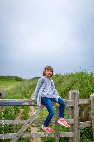 Girl sitting on the fence in Pemprokeshire countryside, Wales photo