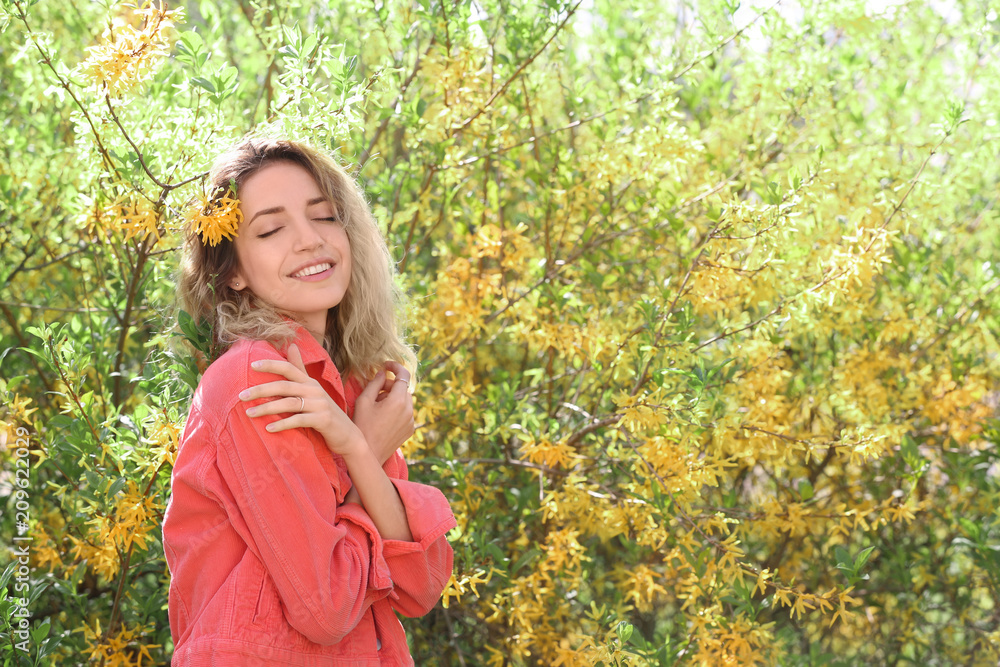 Attractive young woman posing near blossoming bush on sunny spring day Attractive young woman posing near blossoming bush on sunny spring day