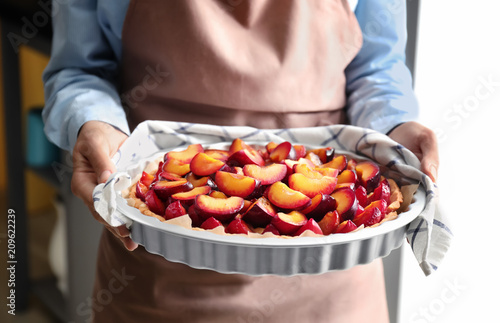 Woman holding delicious pie with plums, closeup