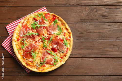 Tasty hot pizza with meat on wooden background, top view