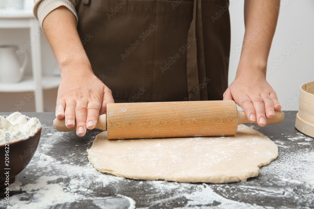 Woman rolling dough on table, closeup