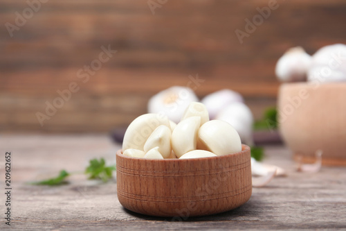 Wooden bowl with ripe garlic cloves on table