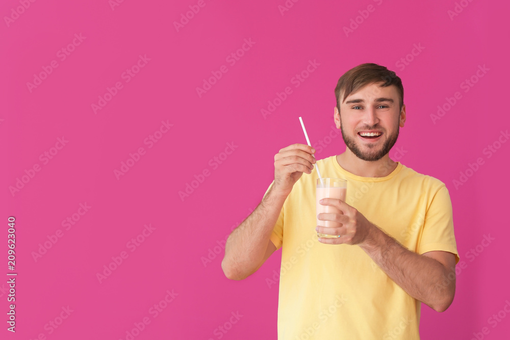 Young man with glass of delicious milk shake on color background Young man with glass of delicious milk shake on color background