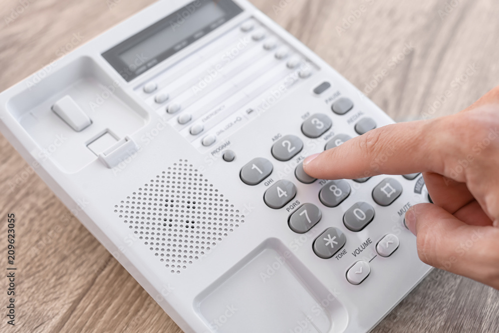 Man dialing number on telephone at table Man dialing number on telephone at table