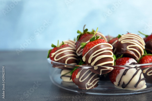 Plate with chocolate covered strawberries on table, closeup