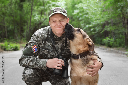 Man in military uniform with German shepherd dog, outdoors