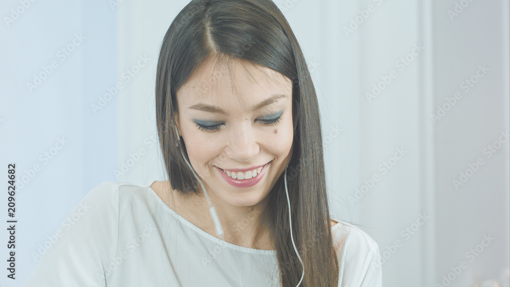 Happy young woman inserting earphones into her ears and enjoying music Happy young woman inserting earphones into her ears and enjoying music