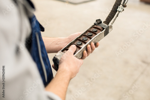 Close-up of unrecognizable construction worker holding remote control of overhead crane while operating equipment at workplace