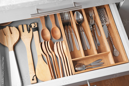 Photo Set of cutlery and wooden utensils in kitchen drawer