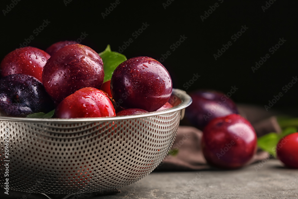 Strainer with ripe juicy plums on dark background Strainer with ripe juicy plums on dark background