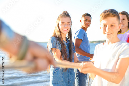 Bild auf Leinwand Group of children pulling rope during tug of war game on beach