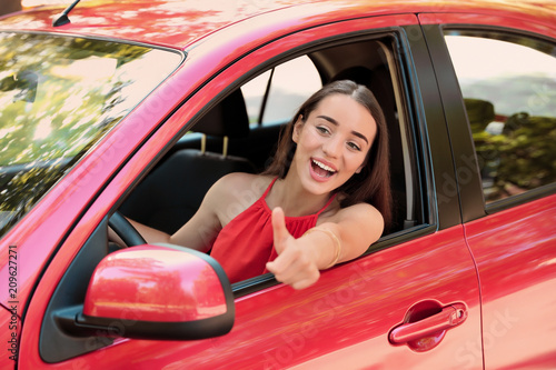 Happy young beautiful woman driving modern car