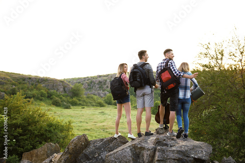 Group of young people with backpacks in wilderness. Camping season
