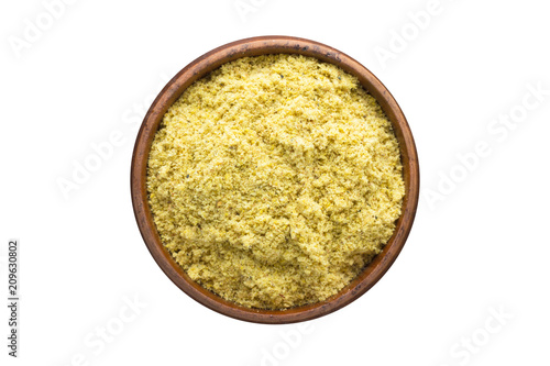 mustard powder spice in wooden bowl, isolated on white background. Seasoning top view