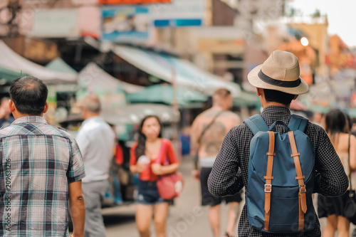 Young man traveling with hat, Asian hipster traveler walking at famous backpacker street in Bangkok (Khao San road), landmark and popular for tourist attractions in Thailand. Travel concept © Jo Panuwat D