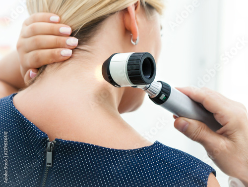 Examination of the patient's skin by a dermatologist using a dermatoscope