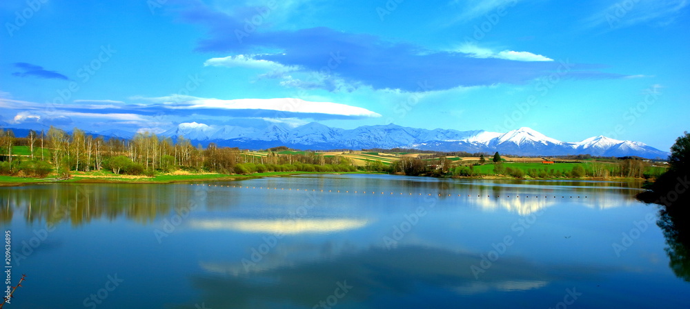 Foto de 北海道、美瑛町の水沢ダムより見る十勝岳連峰の雪渓風景 do Stock Adobe Stock