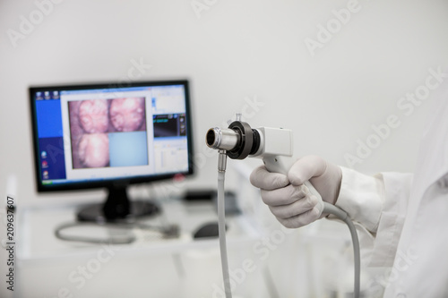 Videorecdoscope for visual diagnosis in the hand of a proctologist on the background of an unsharpened monitor.