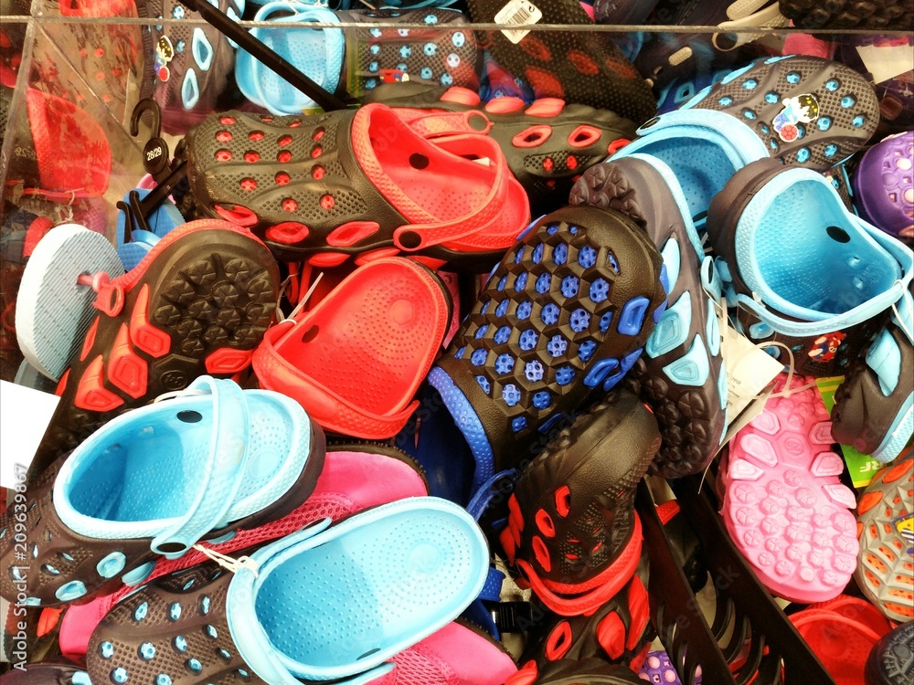 Rack with lots of pairs of childrens soft rubber sandals or