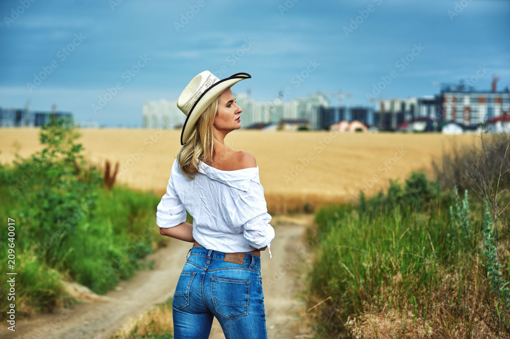 Young woman in casual clothes for a walk in a field of wheat , a woman in a stylish hat