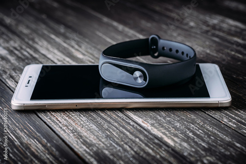 Black fitness tracker on white smartphone