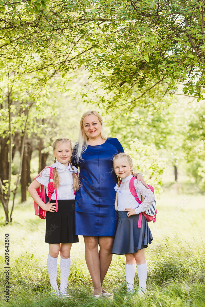 Fototapeta premium happy mom hugging two daughters Schoolgirls outdoors