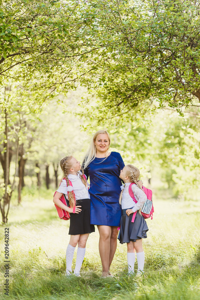Fototapeta premium happy girls in school uniform hugging mom outdoors