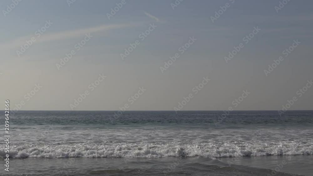 Waves rolling in from the ocean on a clear day with atmospheric mist in the background