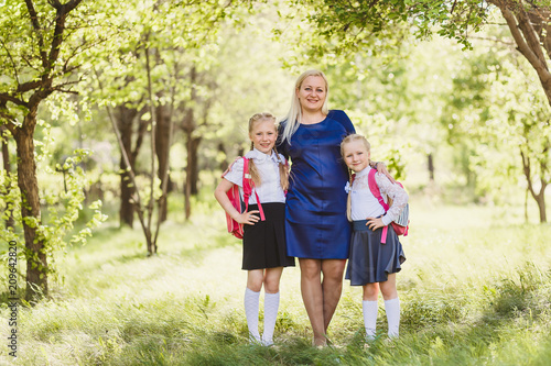 happy mom hugs kids in school uniform outdoors © Alyona