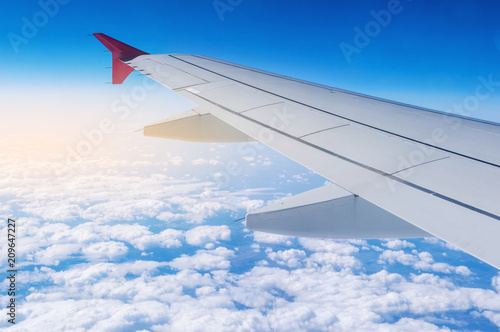 Wing of airplane in flight on a background of clouds. Concept of travel and flights to new countries