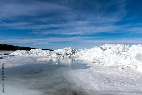frozen lake covered with stack of ice floes and blue sky