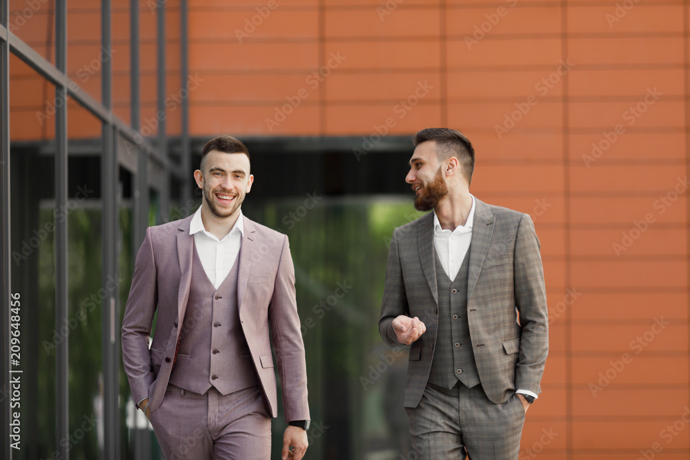 Two smiling young businessmen walking and talking in the city Two smiling young businessmen walking and talking in the city