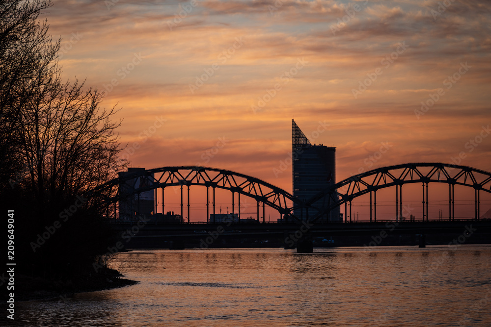 railroad metal bridge silhouette over river of Daugava in Riga, Latvia in dark red sunet railroad metal bridge silhouette over river of Daugava in Riga, Latvia in dark red sunet