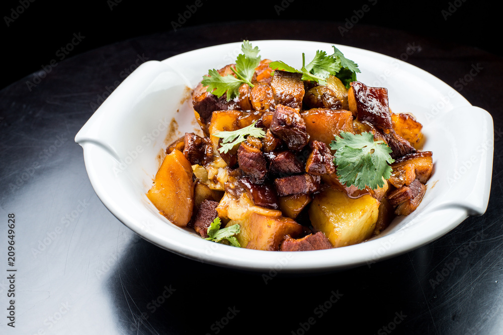 Chinese beef stew with young potatoes in sweet sauce, in white plate on black background Chinese beef stew with young potatoes in sweet sauce, in white plate on black background