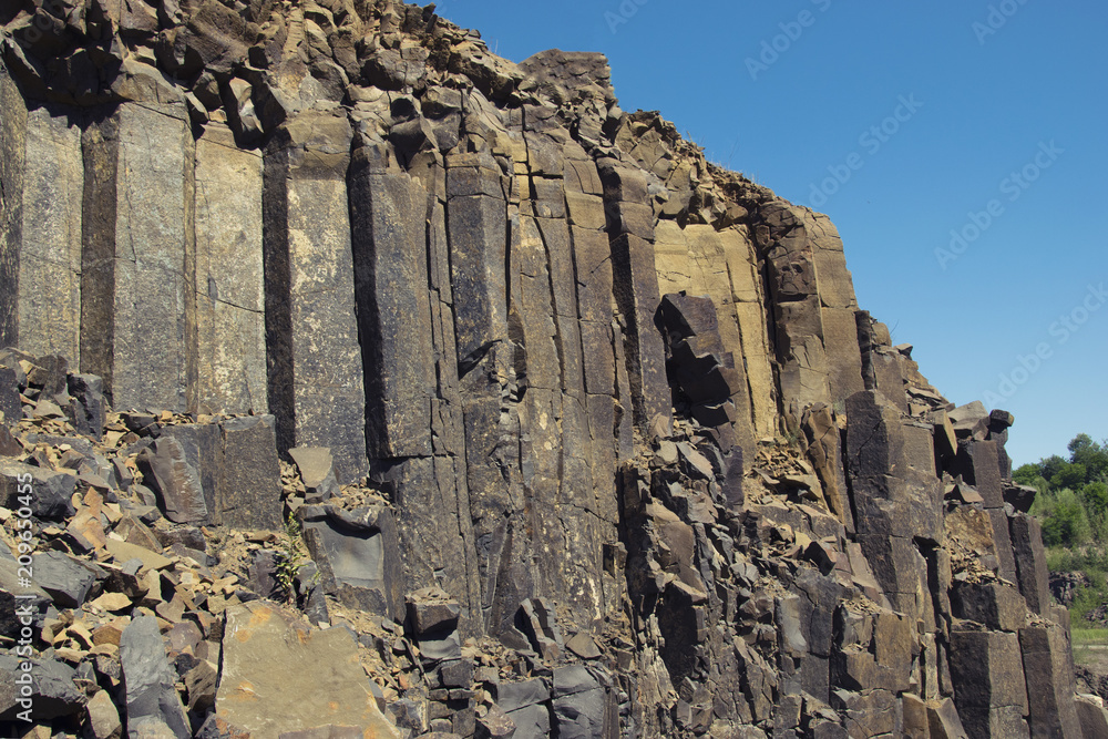 Tall and textured basalt rocks on the blue sky background