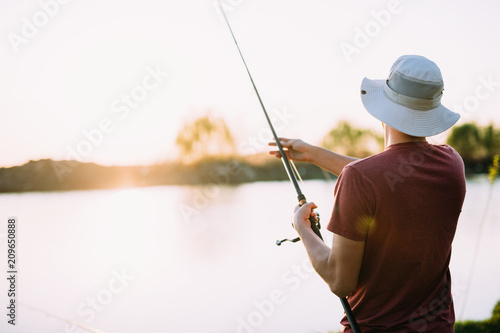 Young man fishing on lake at sunset enjoying hobby © NDABCREATIVITY