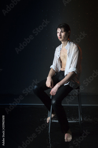 Portrait of attractive young man brunette in wet clothes under droplets of the rain. Studio photo © keleny