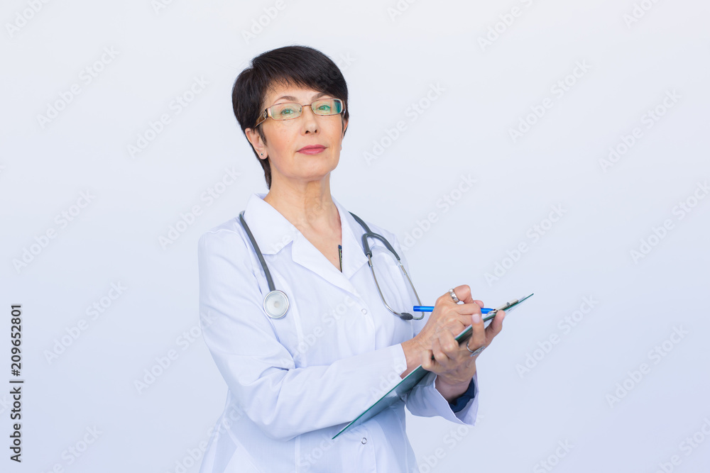 Portrait Of Female Doctor Writing On Clipboard Over a white background Portrait Of Female Doctor Writing On Clipboard Over a white background