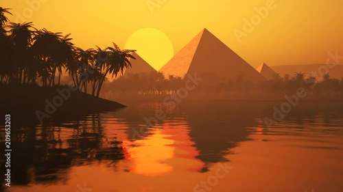 Lake with palms, sand, and silhouettes of the ancient pyramids on the horizon. photo