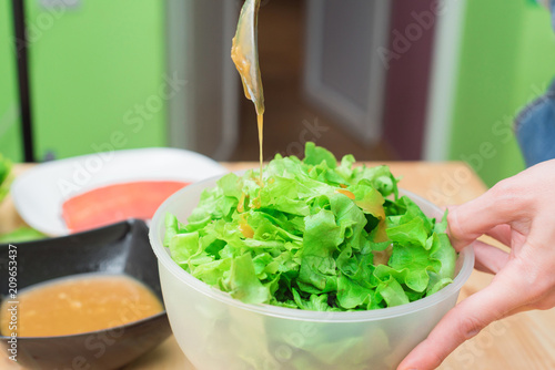 Female hands adding sauce to lettuce from lettuce leaves. Home kitchen. Tasty healthy and healthy food photo