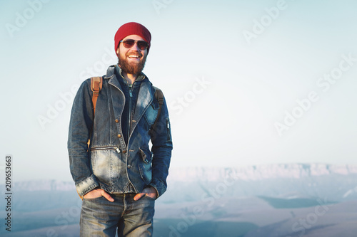 Hipster young man with beard and mustache wearing sunglasses posing against the background of mountains photo