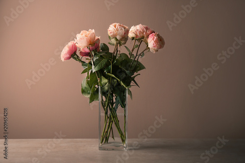 Fototapeta Naklejka Na Ścianę i Meble -  Vase with bouquet of beautiful roses on table against color background