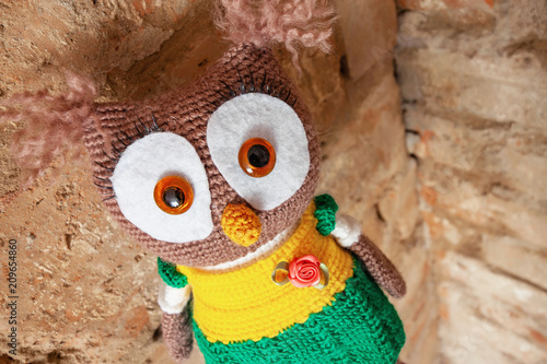 Handmade toy owl on a brick wall background photo