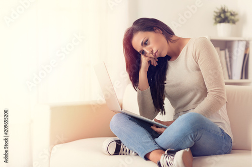 Bored woman using a laptop sitting on a couch Free Download Bored woman using a laptop sitting on a couch - GFXLoad